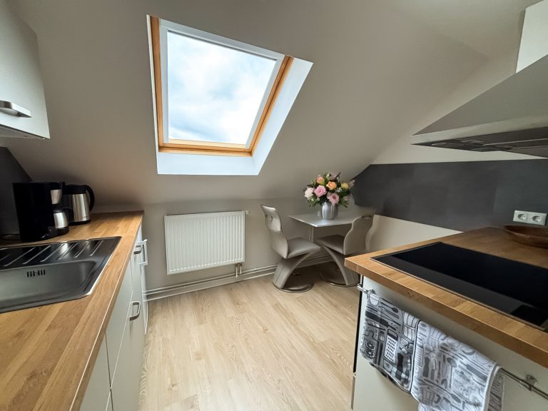 Küche Küche in der Ferienwohnung Juliane. Küchenzeile mit Herd und Ceranfeld, Dunstabzugshaube, Kühlschrank, Spüle, Esstisch mit 2 Stühlen.